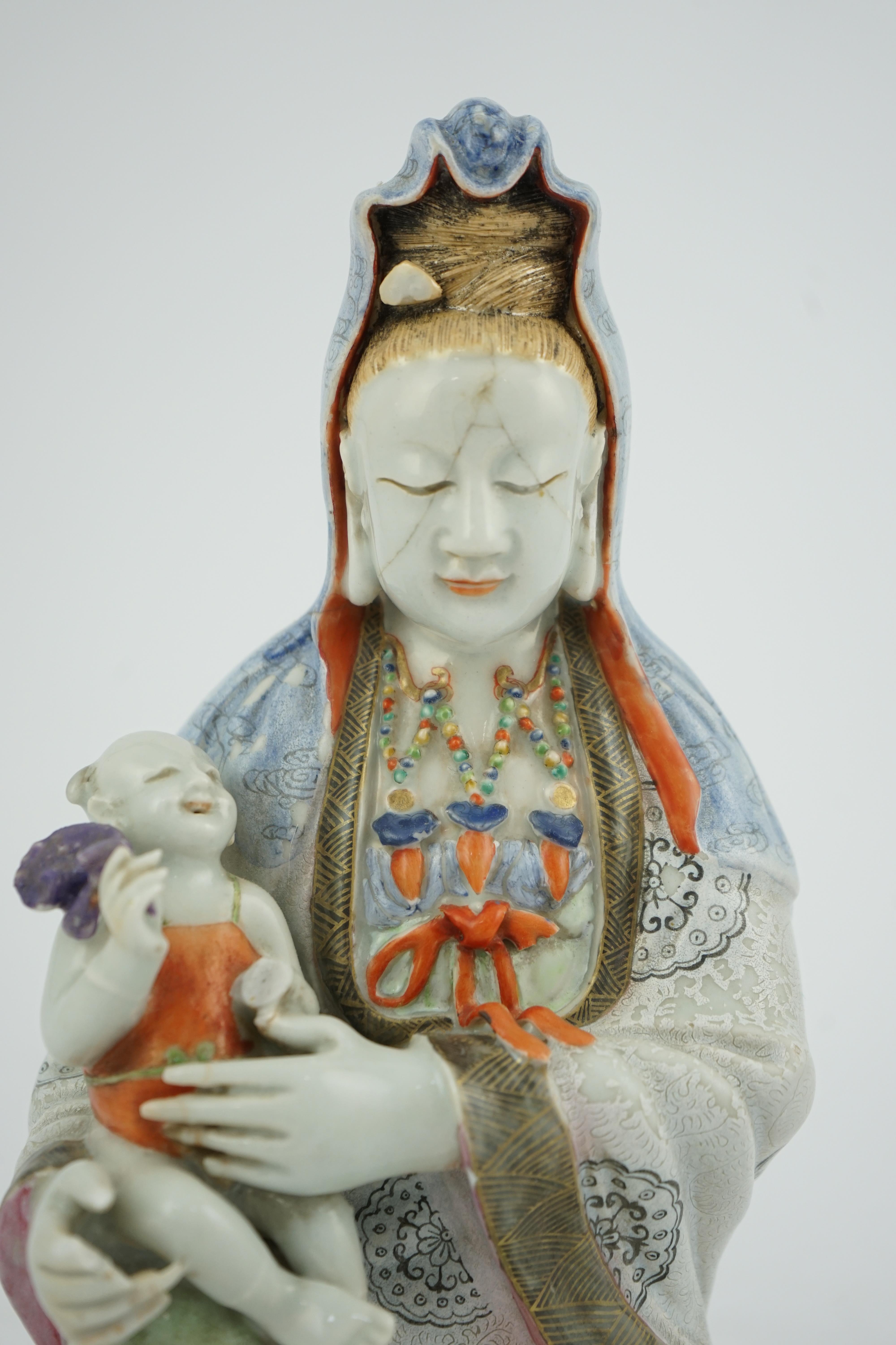 A Chinese enamelled porcelain group of Guanyin holding a child, Qianlong period